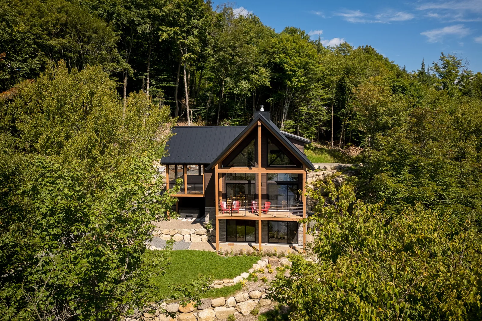 La façade de bois sombre et de pierre du chalet Mont-Blanc, construit par Écohabitations Boréales dans les Laurentides