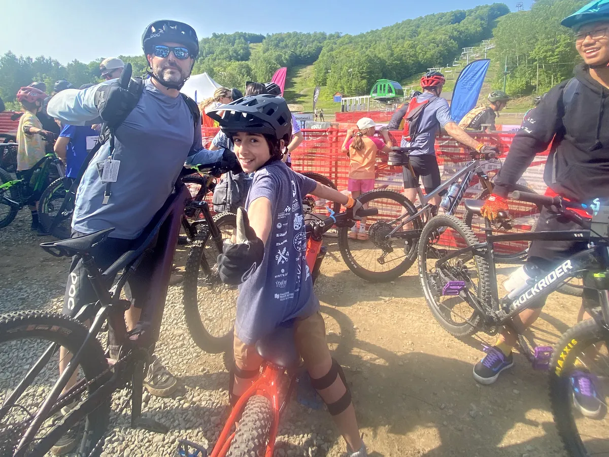 An adult and a child on their mountain bikes give a thumbs-up at the start of Roule à fond, the Fonds Édouard Boivin event